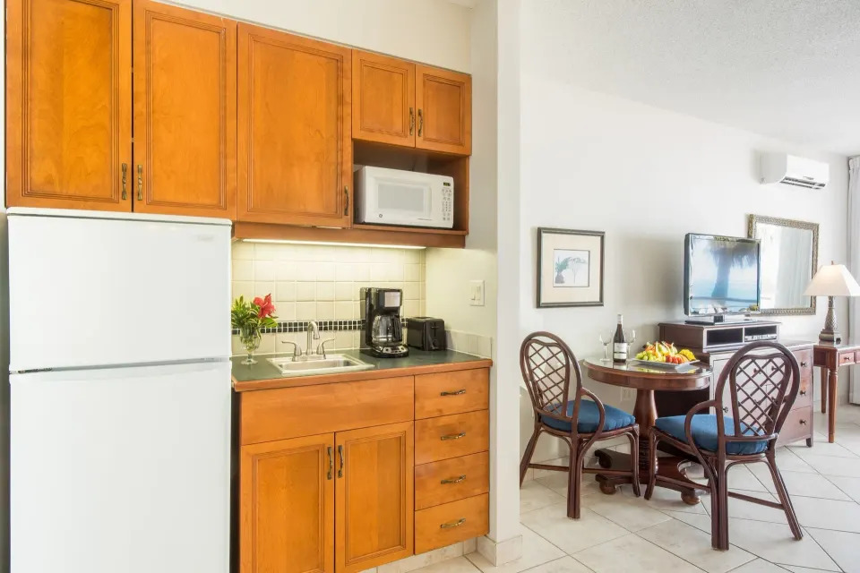Studio Botanical View kitchenette with refrigerator, microwave, sink and dining table at Royal West Indies Resort.