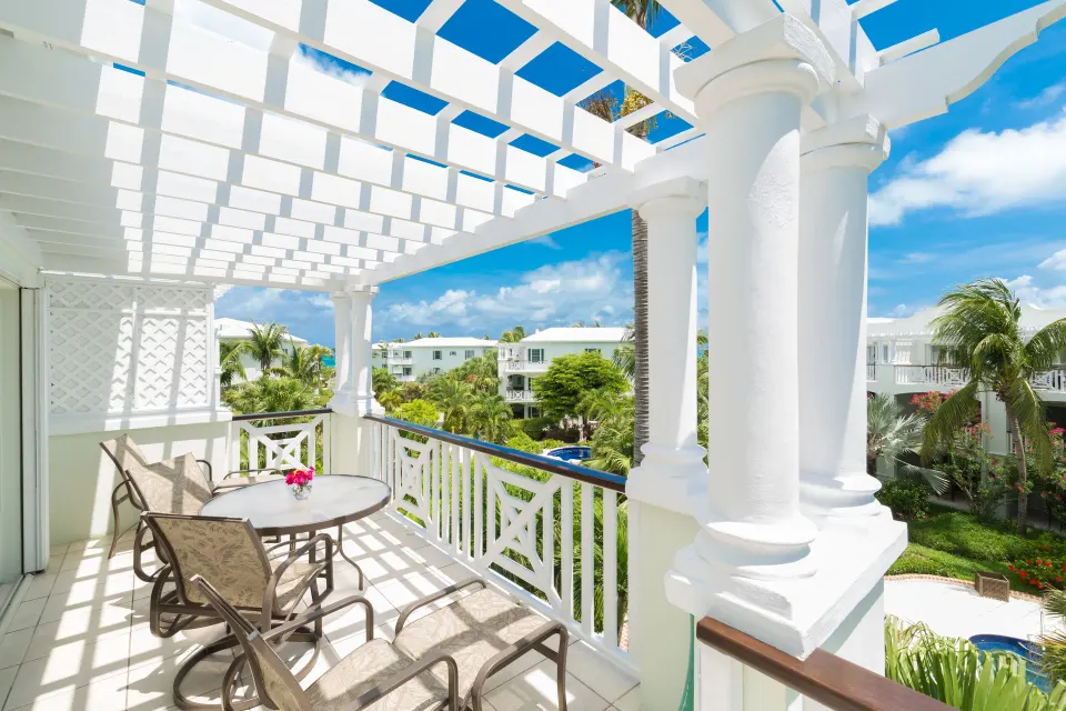 Studio Botanical View balcony with white pergola, patio chairs and landscaped view at Royal West Indies Resort.