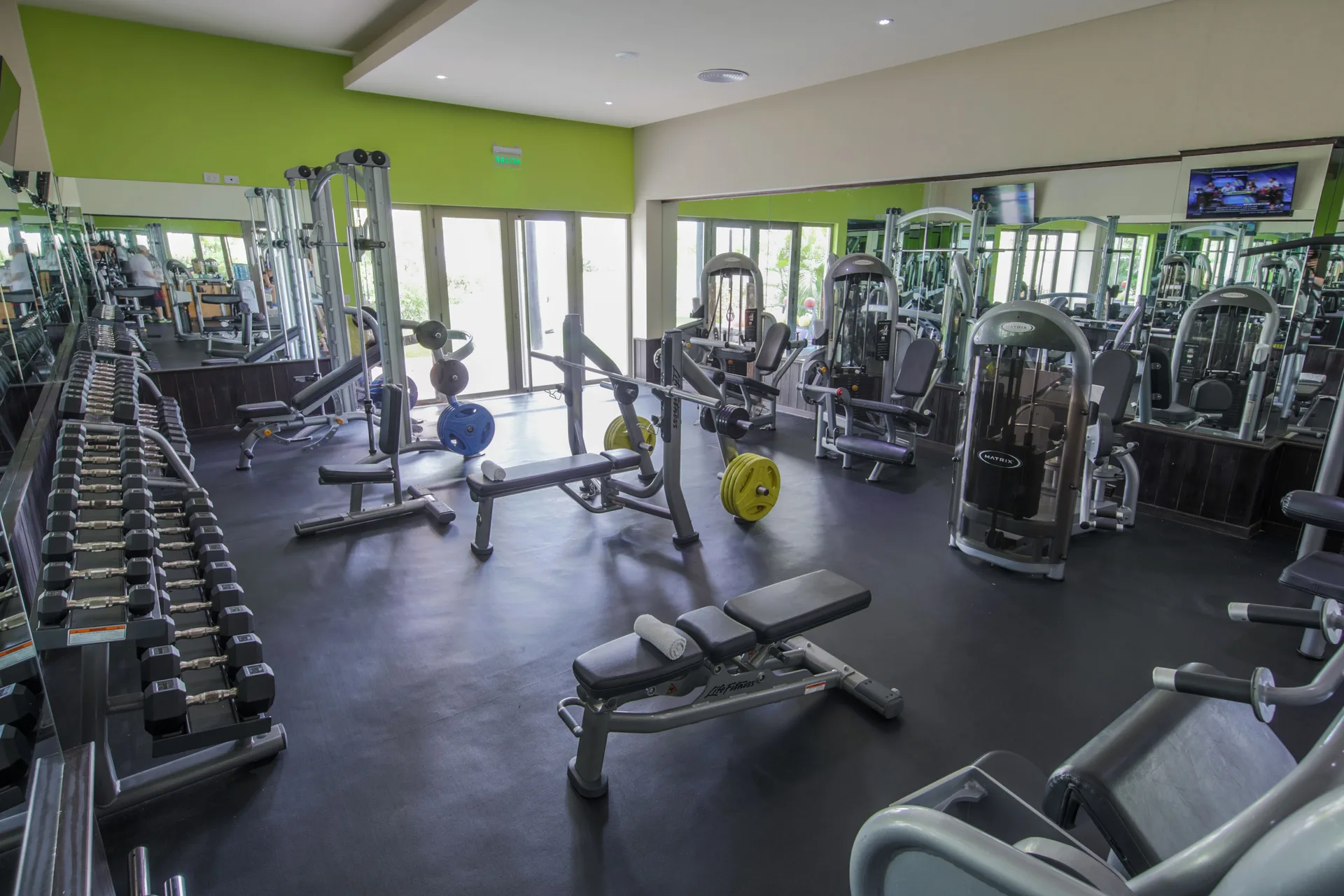 Weight benches, dumbbells, and resistance machines are shown in the gym at Royalton Bavaro Resort & Casino.