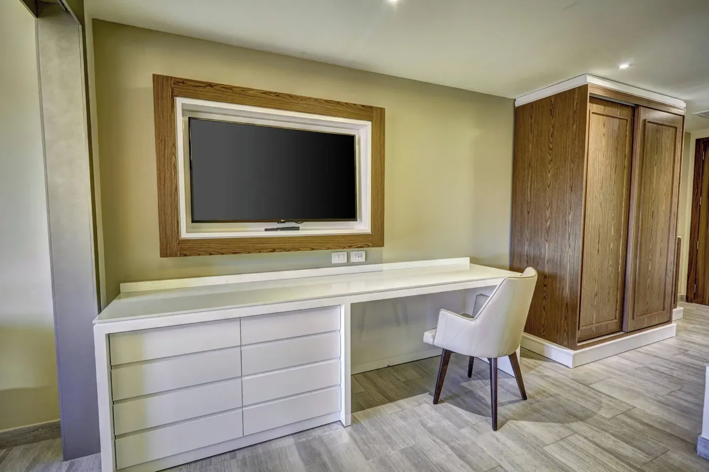Guest room desk, dresser, television, and wardrobe at Royalton Bavaro Resort & Casino.