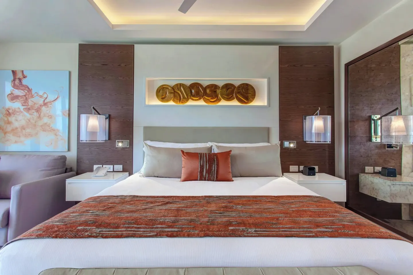 King bed with orange accents and mirrored wall detail at Royalton Bavaro Resort & Casino.