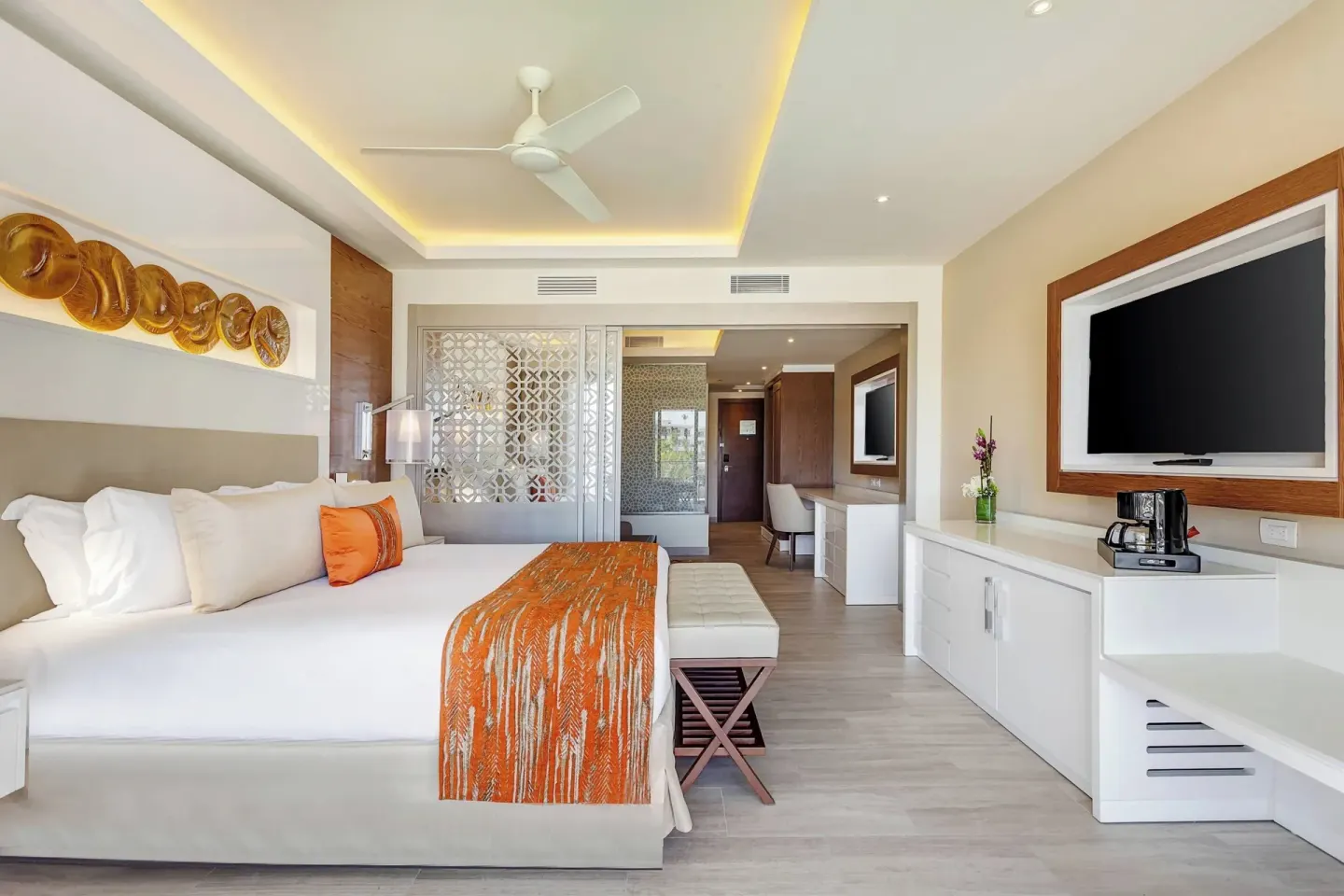 King bed guest room with TV and decorative orange accents at Royalton Bavaro Resort & Casino.