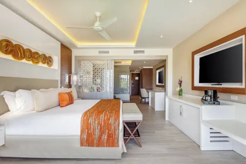 King bed guest room with TV and decorative orange accents at Royalton Bavaro Resort & Casino.