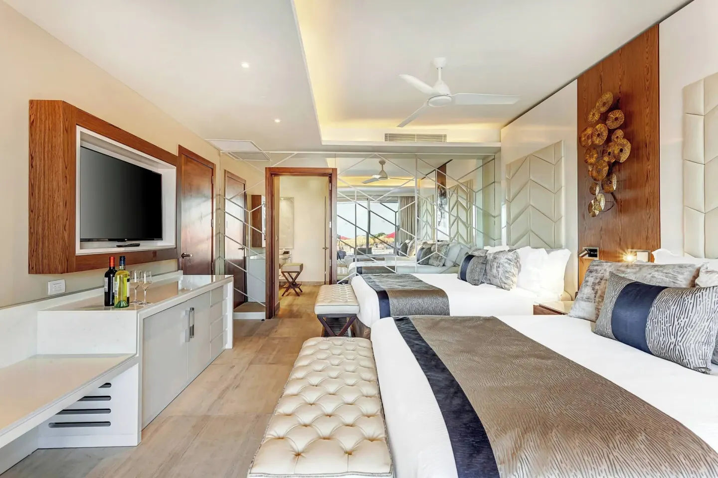 Guest room with two beds, TV and mirrored divider at Royalton Bavaro Resort & Casino.