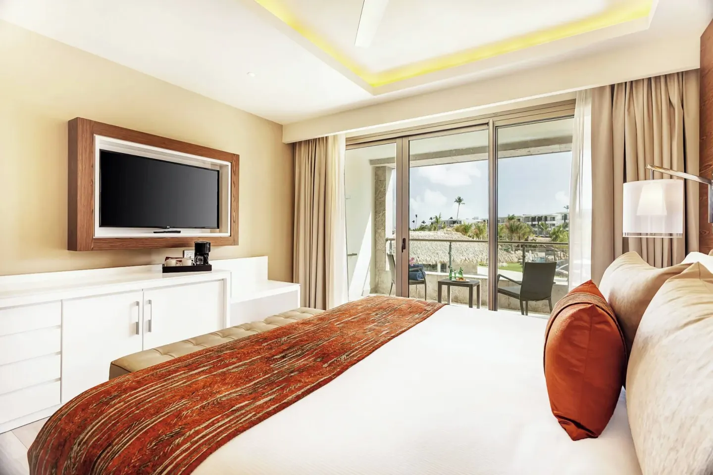 King bed guest room with balcony doors and TV at Royalton Bavaro Resort & Casino.