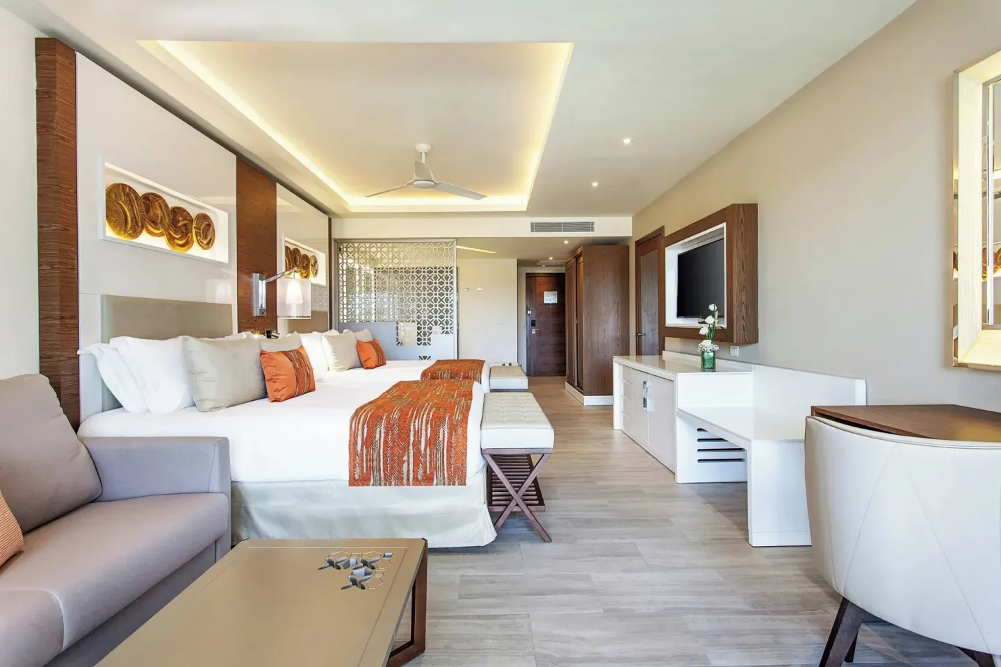 Guest suite with a king bed, sofa, desk, and TV at Royalton Bavaro Resort & Casino.
