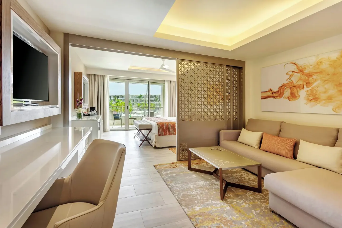 Suite living area with sofa, desk, and bedroom beyond at Royalton Bavaro Resort & Casino.