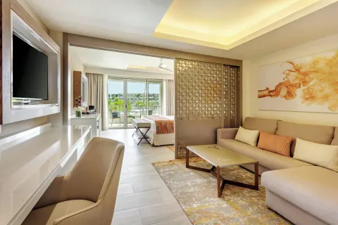 Suite living area with sofa, desk, and bedroom beyond at Royalton Bavaro Resort & Casino.