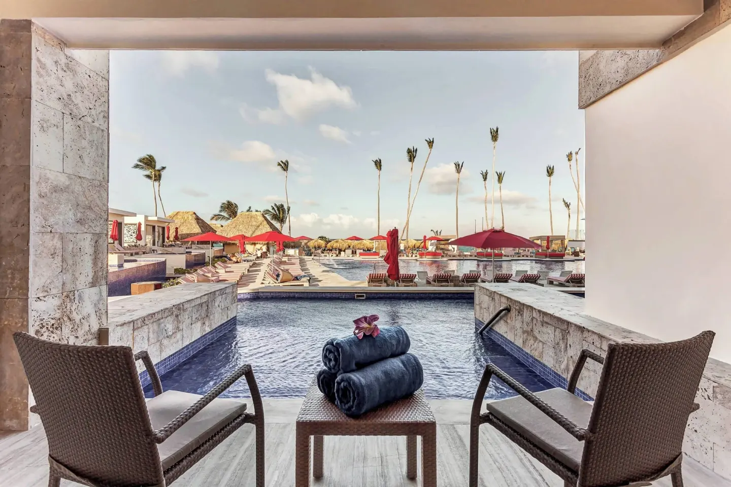 Swim-out terrace facing pools, loungers, and red umbrellas at Royalton Bavaro Resort & Casino.
