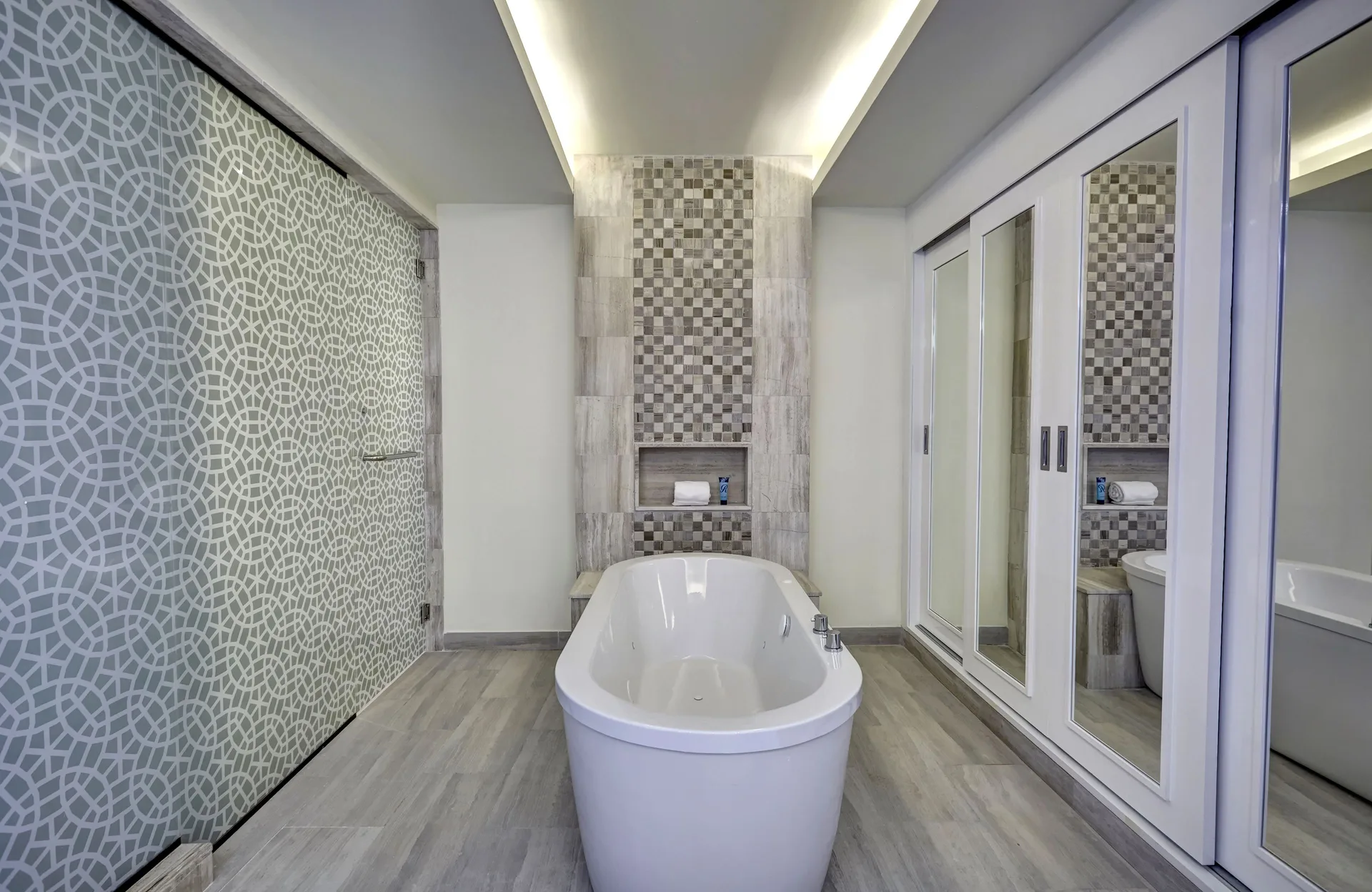 Freestanding bathtub and patterned shower glass at Royalton Bavaro Resort & Casino.