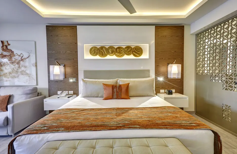 Luxury Junior Suite king bed at Royalton Bavaro Resort & Casino with sofa and decorative screen.