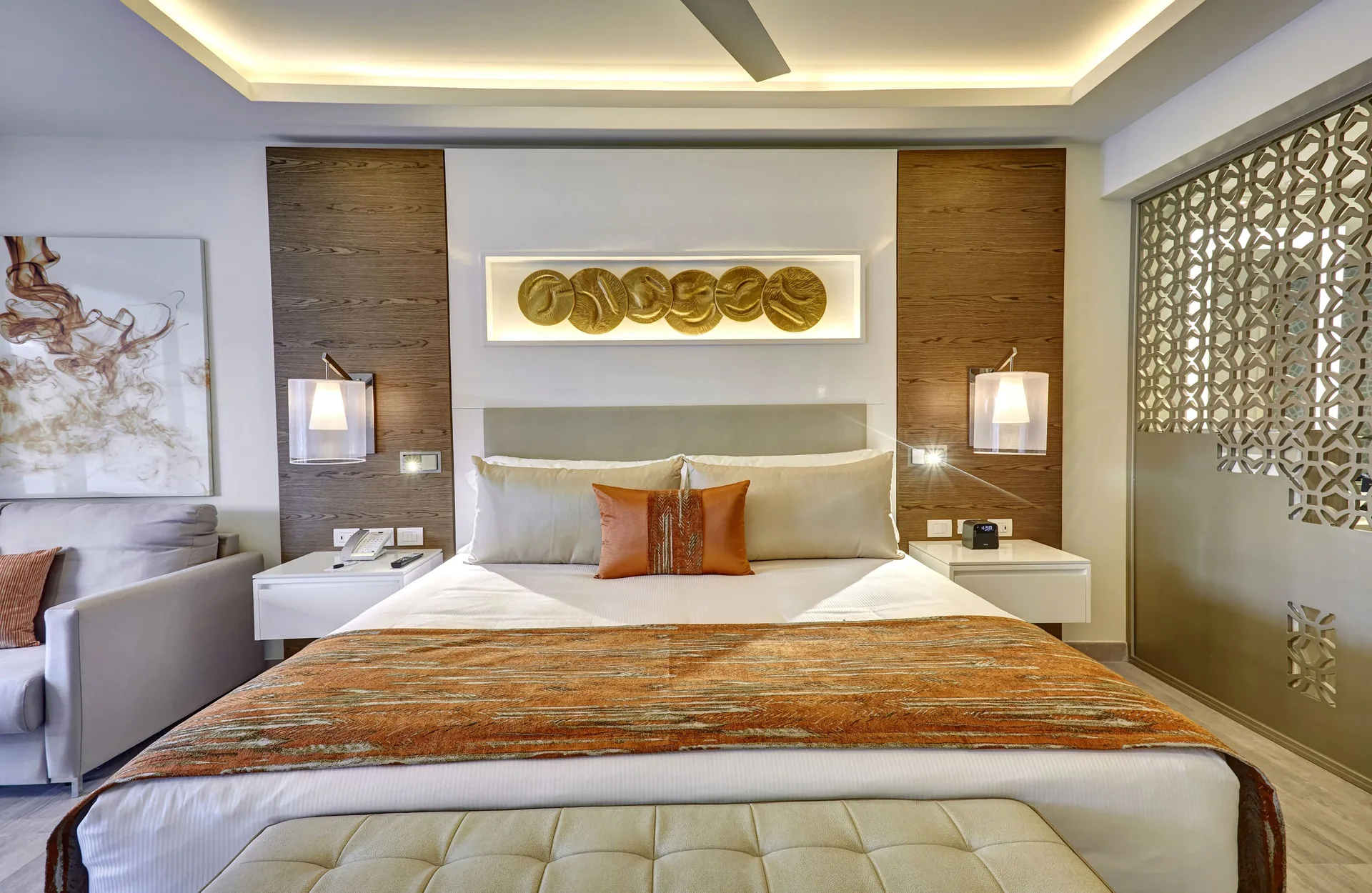 Luxury Junior Suite king bed at Royalton Bavaro Resort & Casino with sofa and decorative screen.