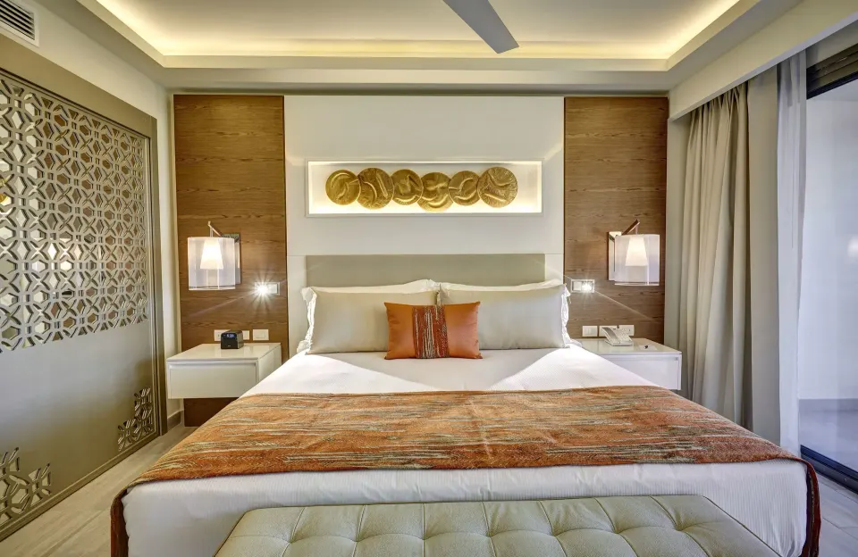 Luxury Junior Suite king bed with balcony doors at Royalton Bavaro Resort & Casino.