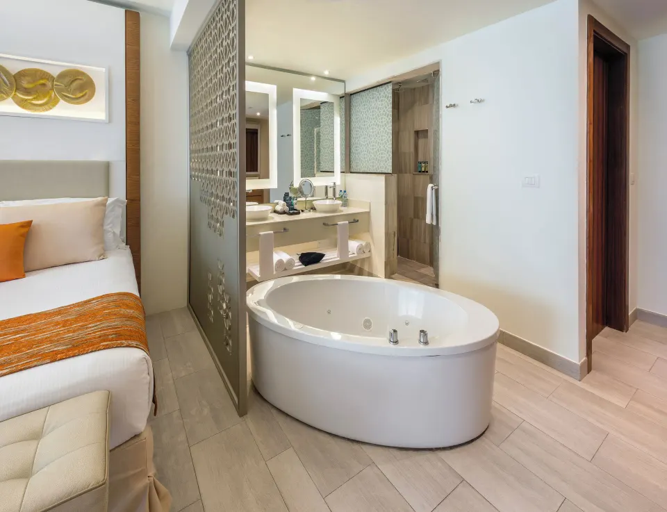 Luxury Junior Suite soaking tub and vanity beside the bed at Royalton Bavaro Resort & Casino.