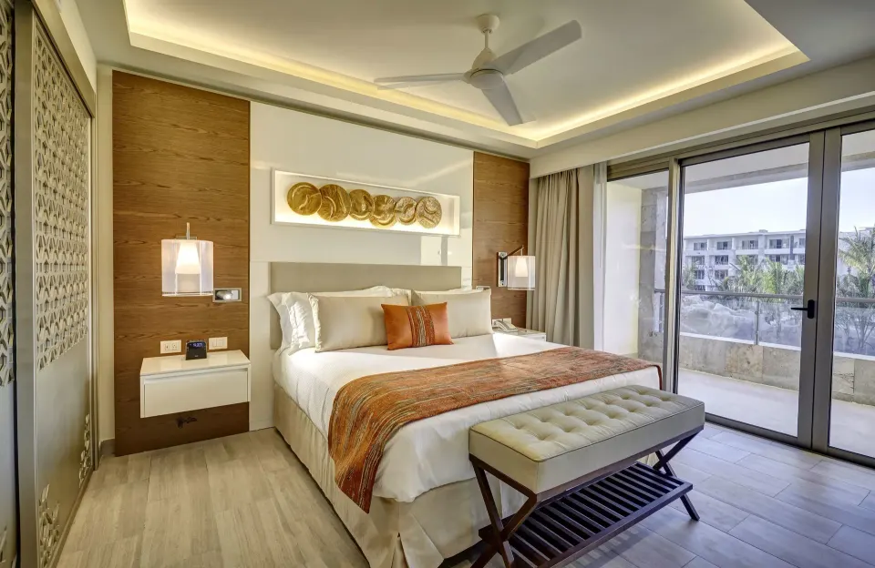 Luxury Junior Suite king bed at Royalton Bavaro Resort & Casino with balcony and resort building view.
