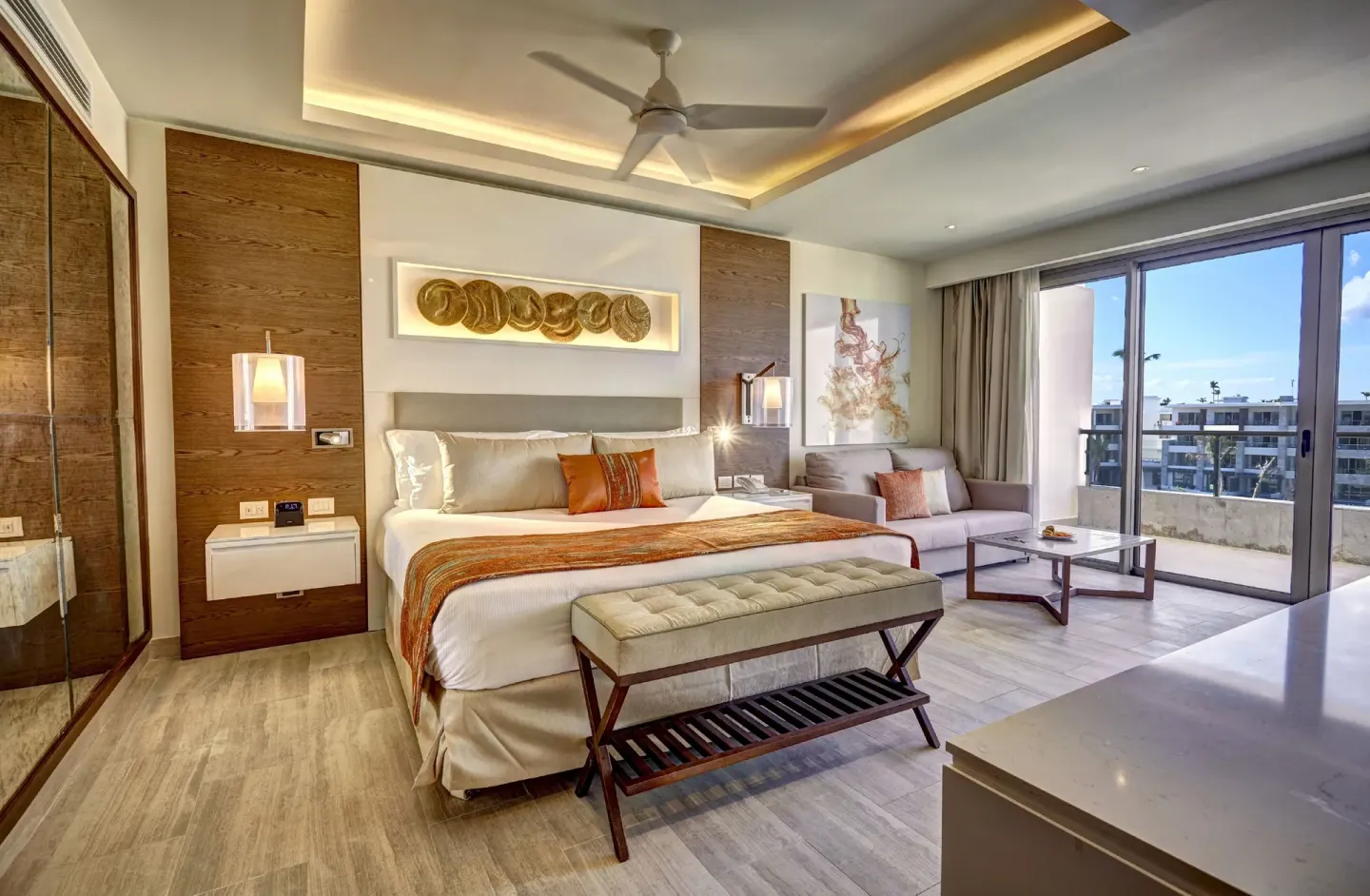 Luxury Junior Suite king bed at Royalton Bavaro Resort & Casino with sofa, table, and balcony doors.