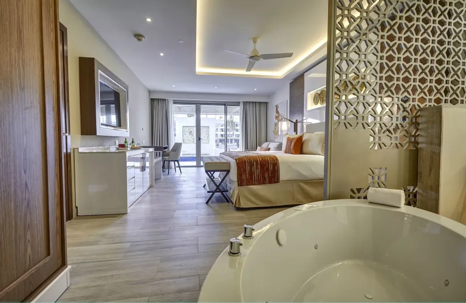Luxury Junior Suite at Royalton Bavaro Resort & Casino with soaking tub in foreground and bed beyond.
