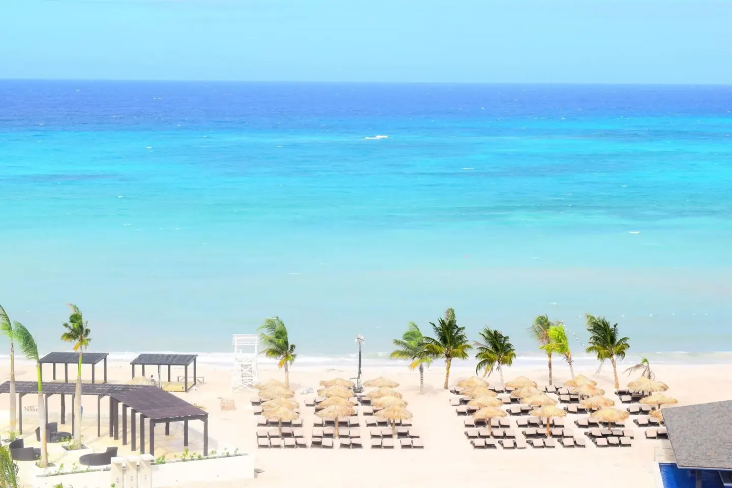 Aerial beach view with loungers and turquoise sea at Royalton Blue Waters Montego Bay.
