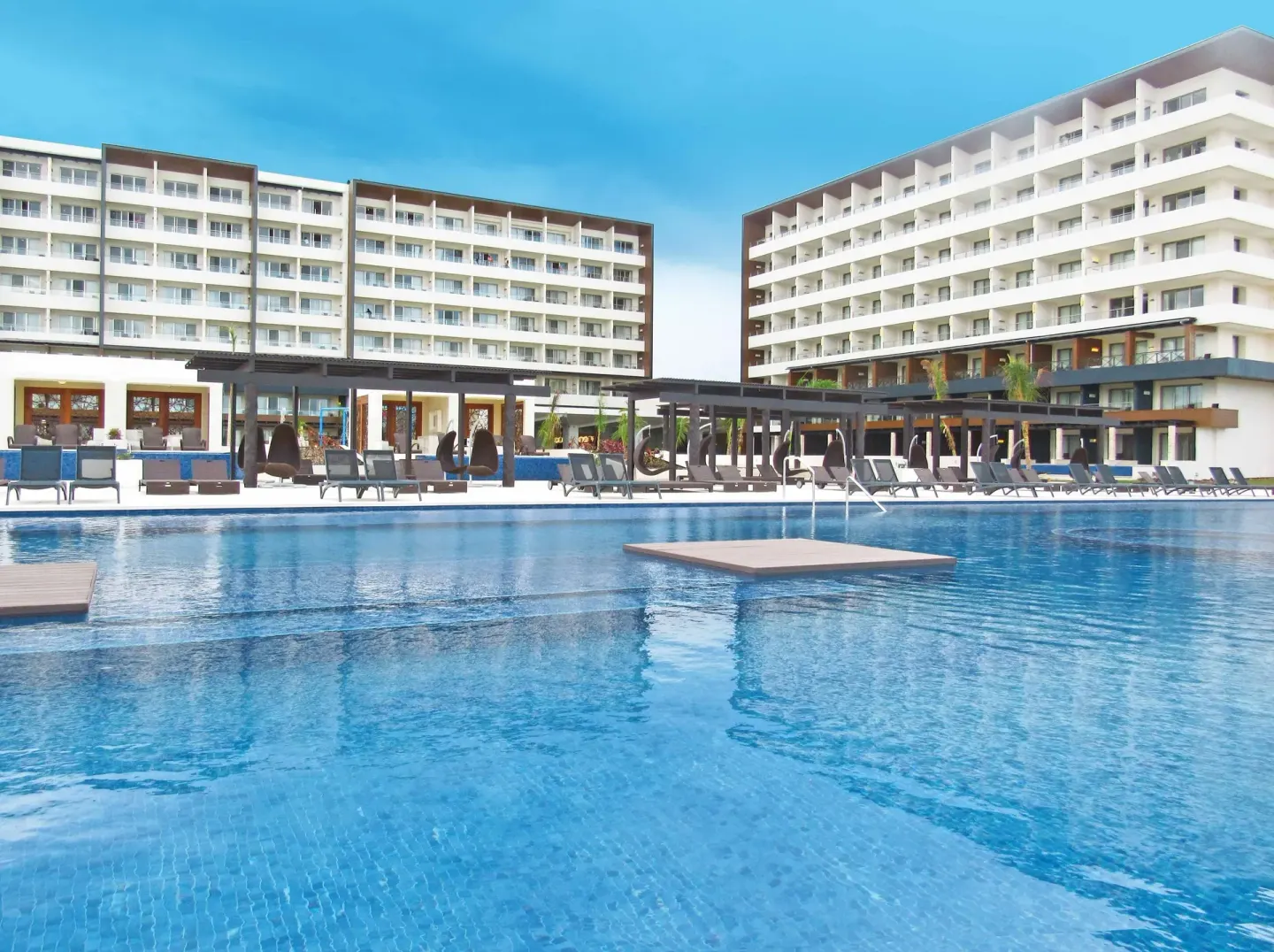 Large resort pool with lounge chairs and guest-room buildings at Royalton Blue Waters Montego Bay.