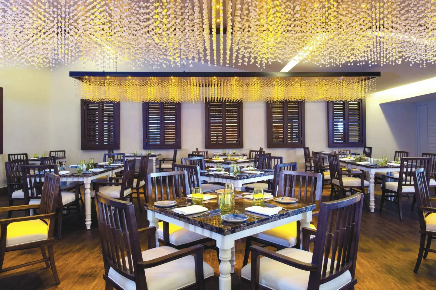Set restaurant tables beneath a decorative ceiling at Royalton Blue Waters Montego Bay.