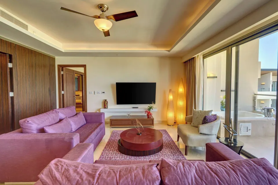 Suite living room with purple sofas and balcony doors at Royalton Blue Waters Montego Bay.
