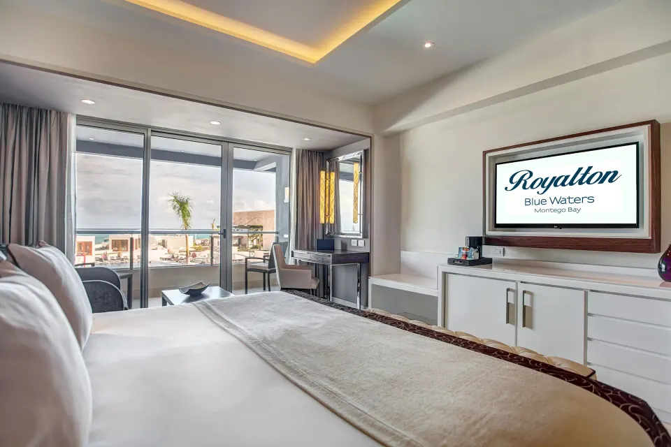 Luxury Junior Suite king bed with ocean-view balcony at Royalton Blue Waters Montego Bay.
