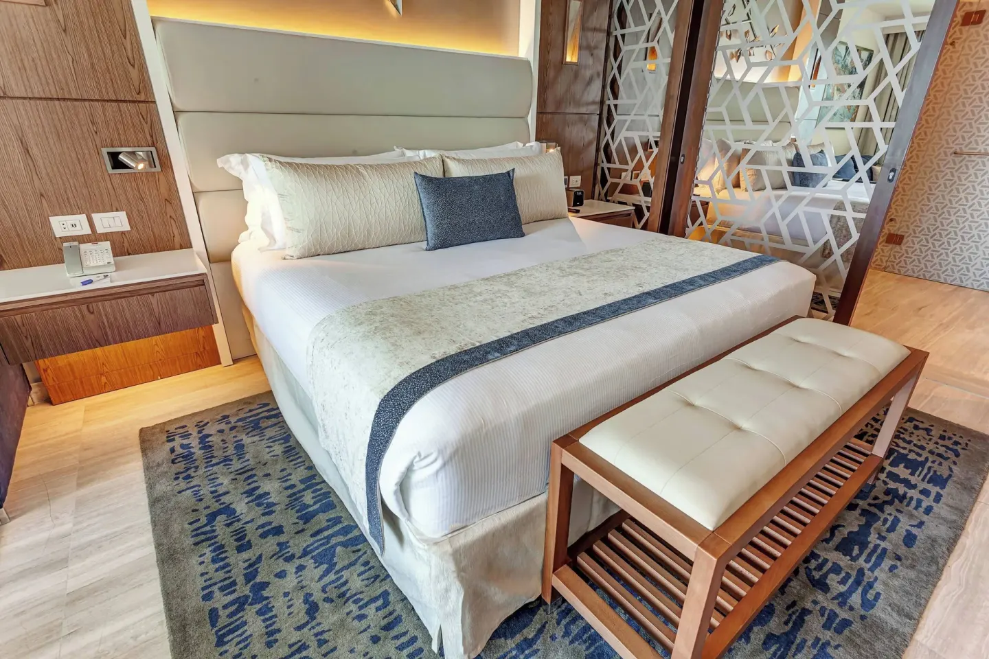 King bed with padded bench and patterned divider in a guest room at Royalton CHIC Cancun.