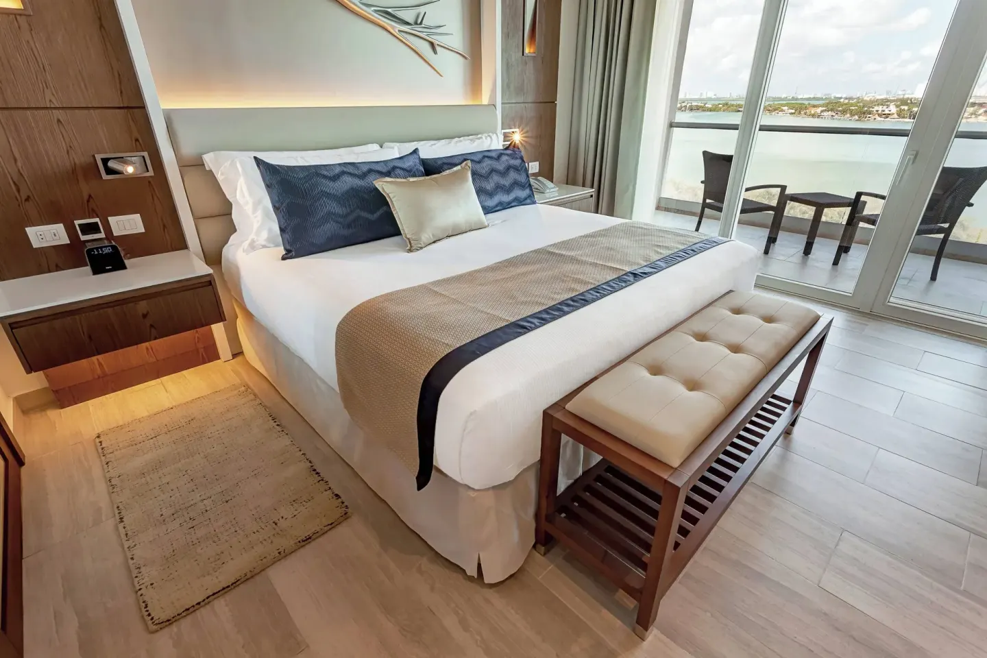 King bed beside balcony doors with lagoon water view at Royalton CHIC Cancun.