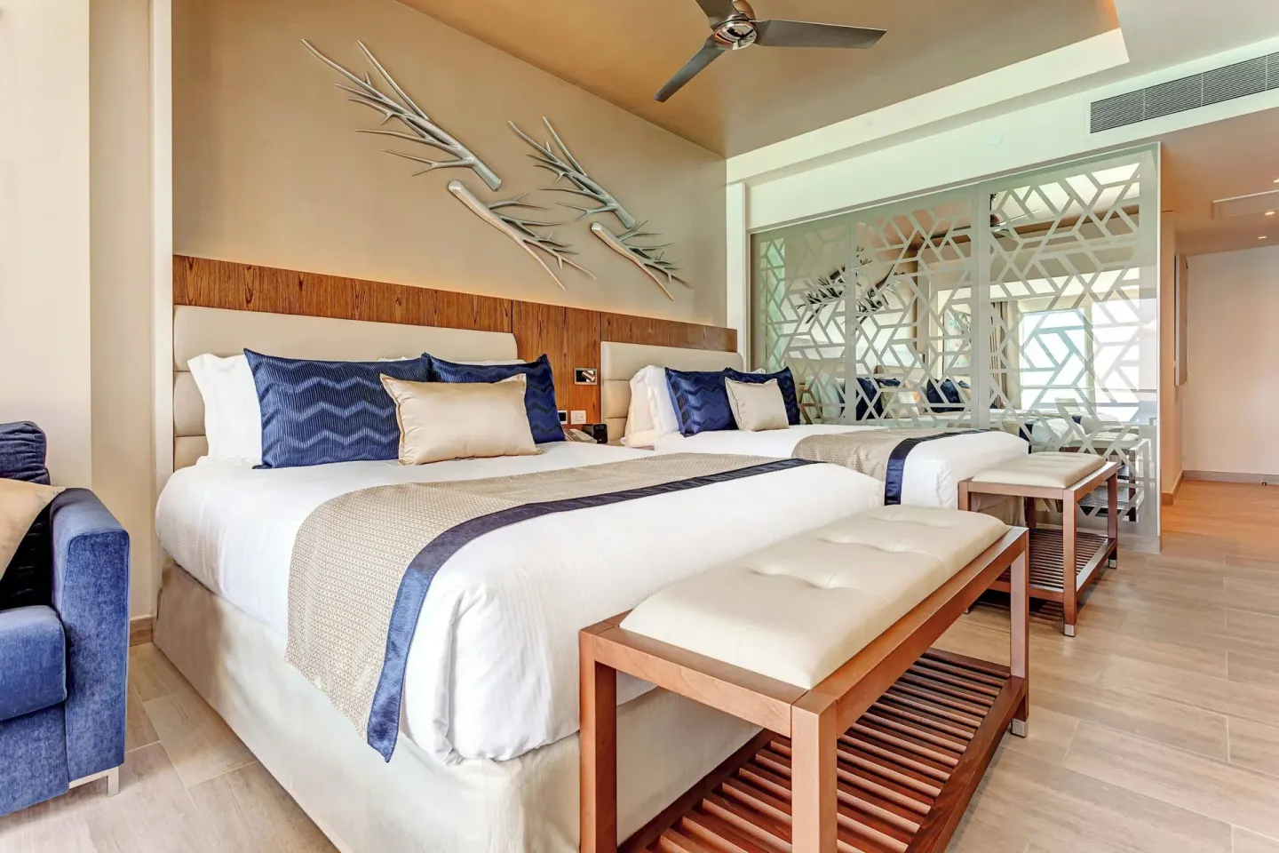Two-bed guest room with benches and blue accents at Royalton CHIC Cancun.