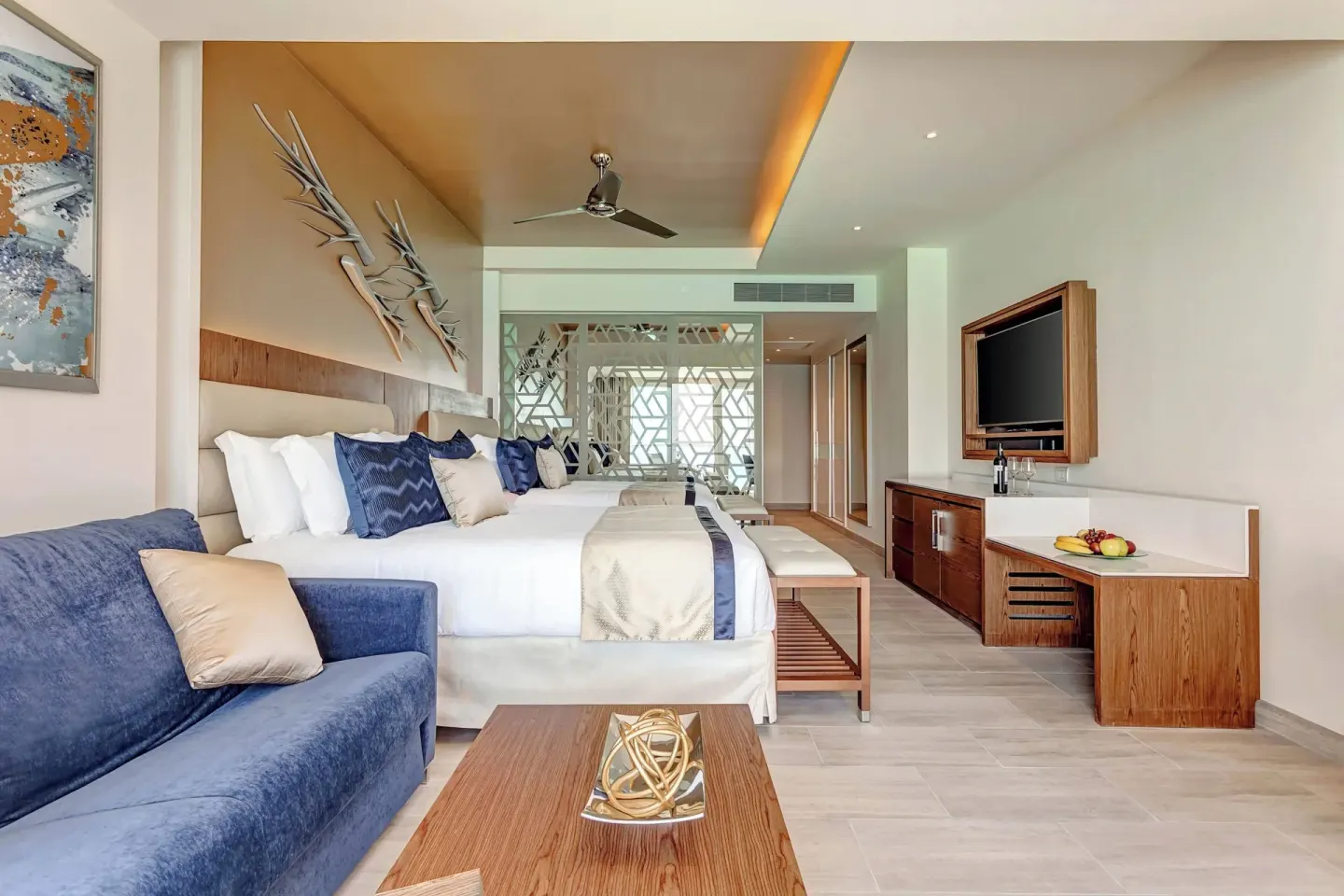 Guest room with two beds, sofa, and TV wall at Royalton CHIC Cancun.