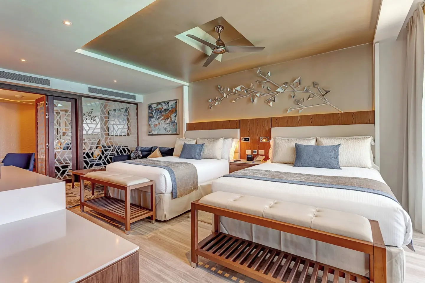Guest room with two double beds, benches and blue accents at Royalton CHIC Cancun.