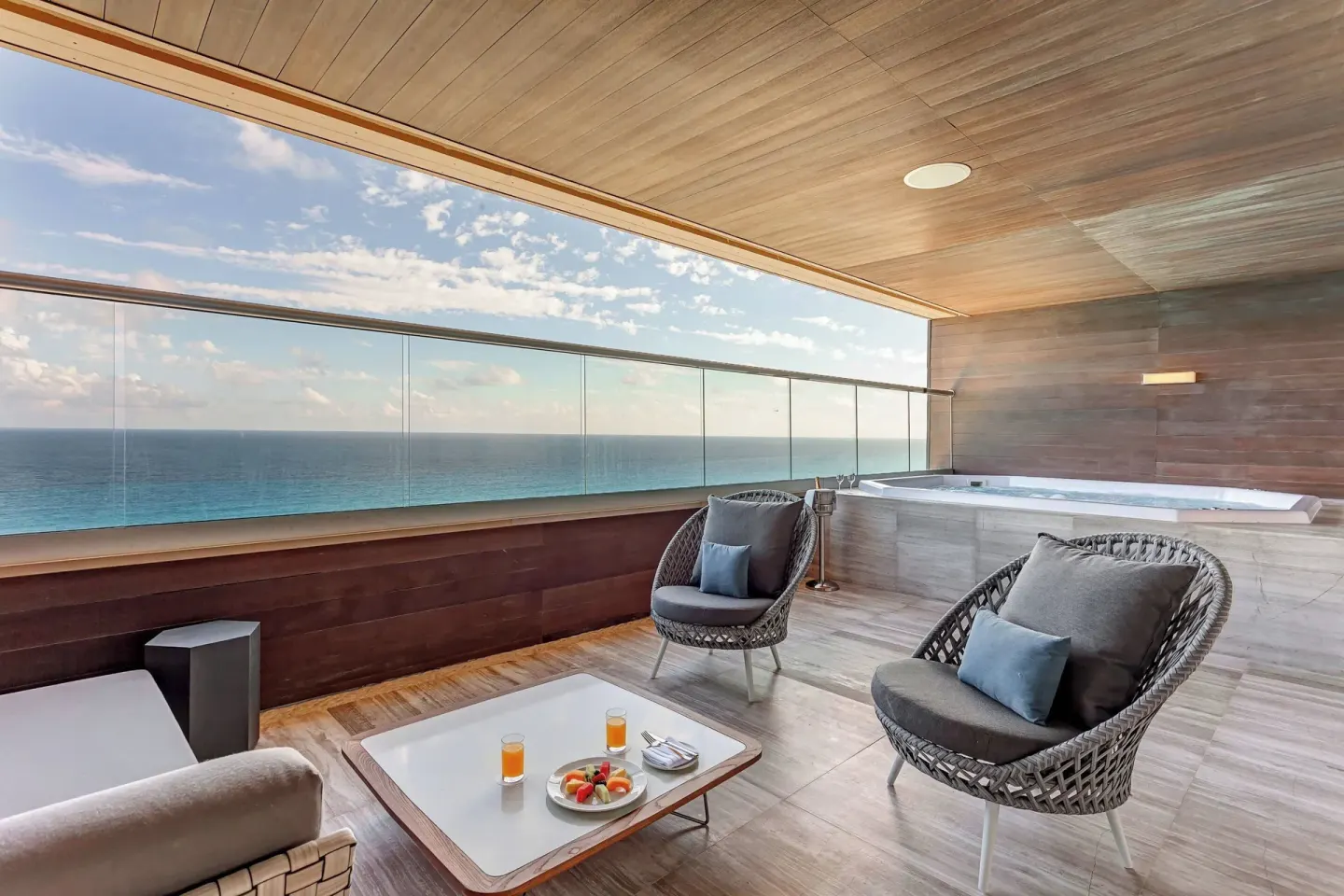 Covered ocean-view terrace with lounge chairs and hot tub at Royalton CHIC Cancun.