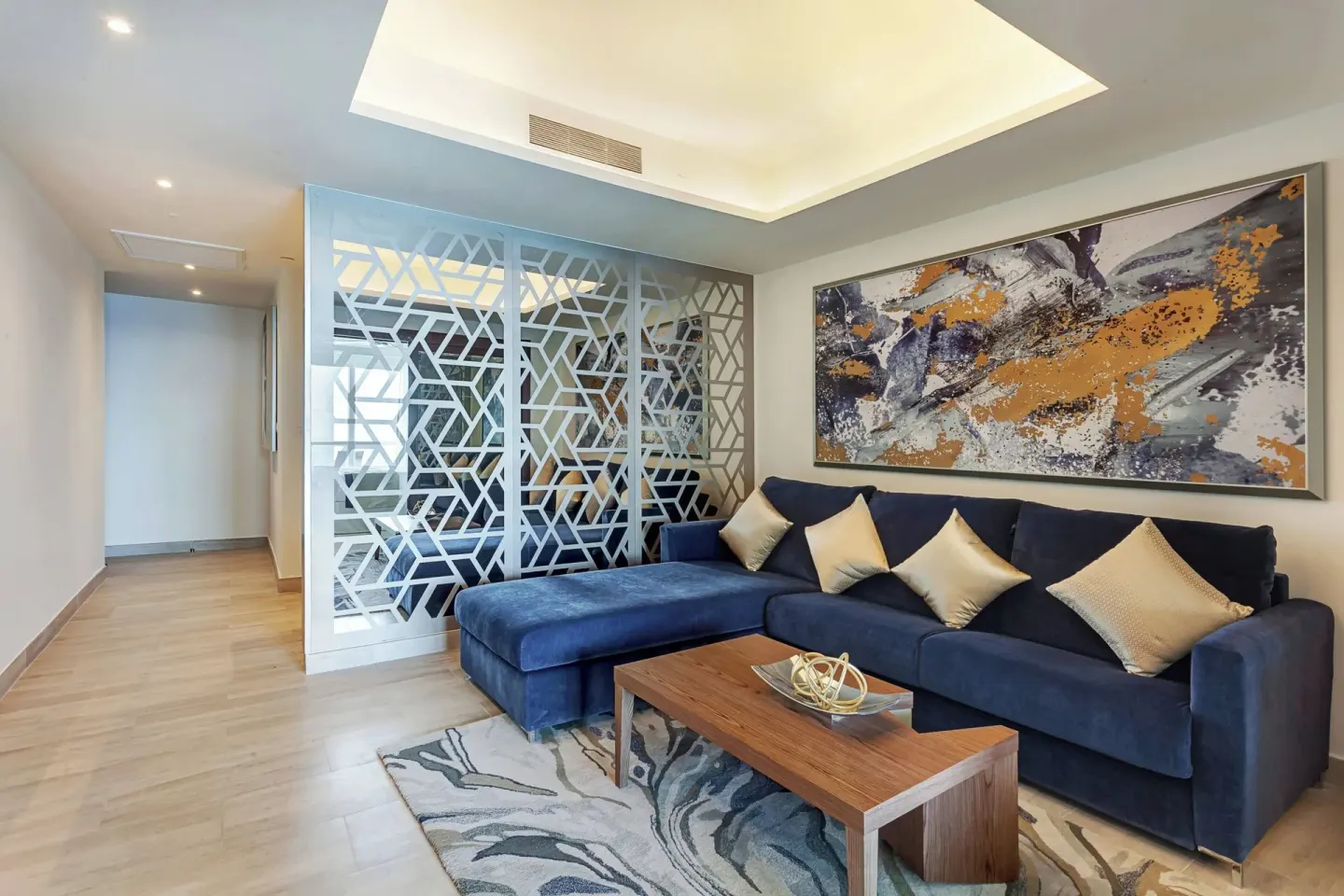 Suite living area with blue sectional sofa and abstract wall art at Royalton CHIC Cancun.