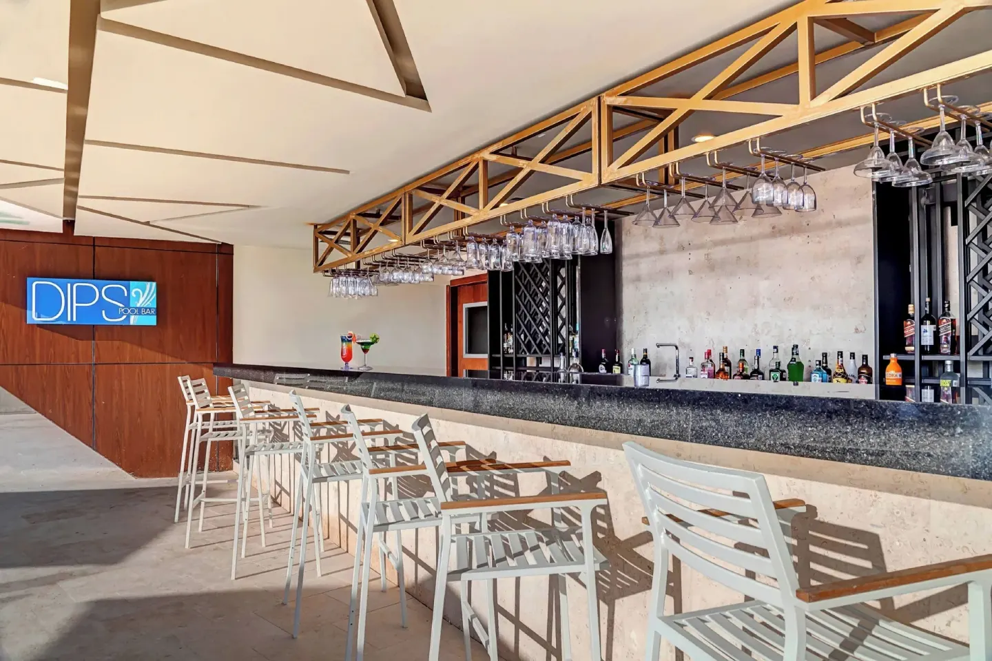 Dips Pool Bar counter with stools and hanging glassware at Royalton CHIC Cancun.