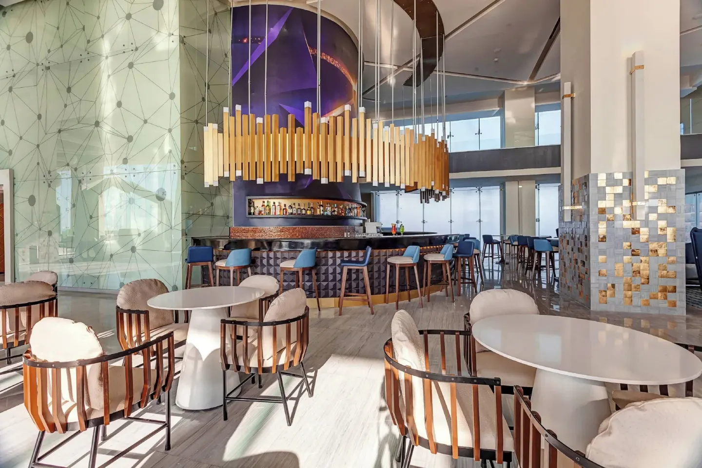 Lobby bar with lounge seating and tall pendant lights at Royalton CHIC Cancun.