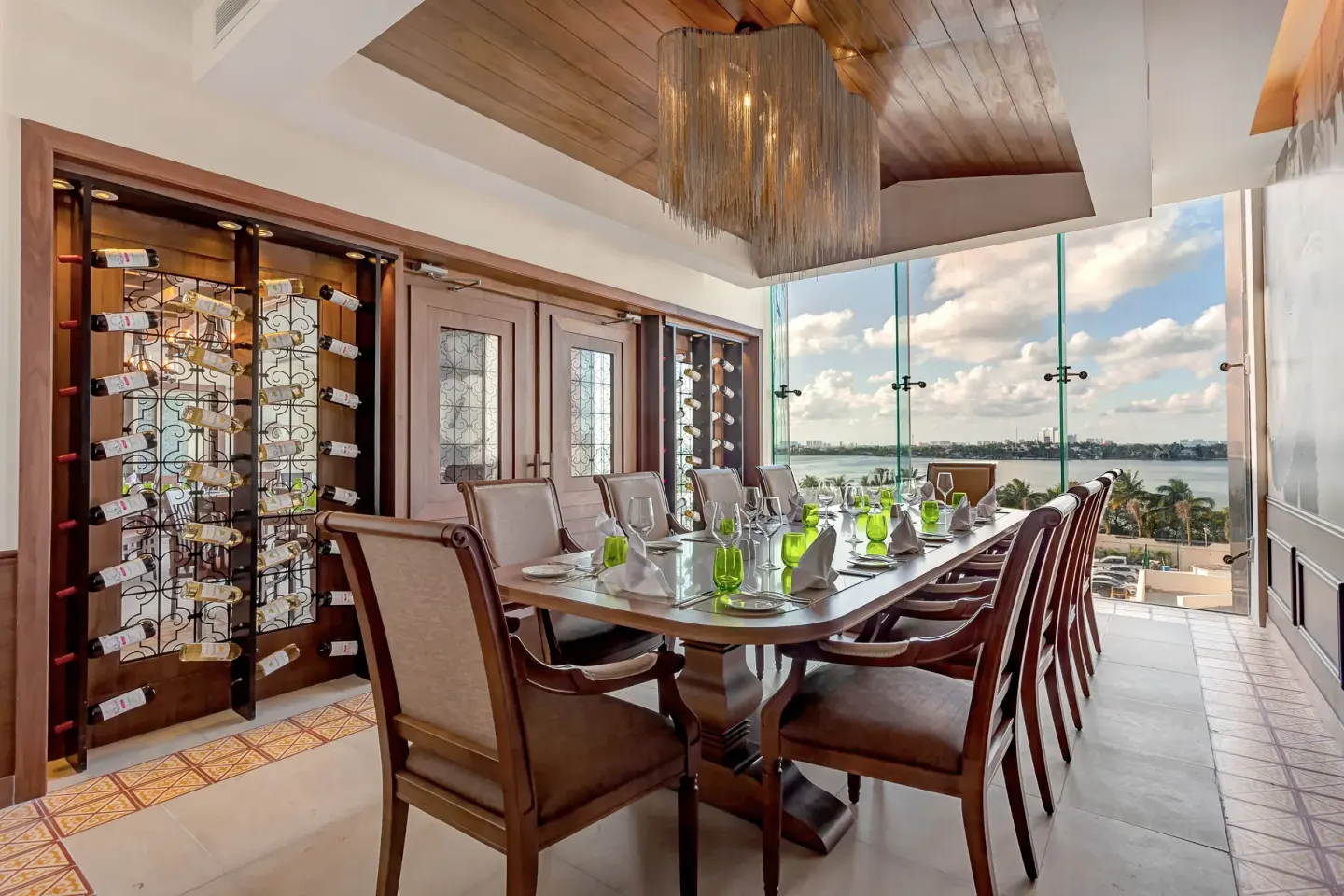 Private dining table beside wine racks and lagoon-facing windows at Royalton CHIC Cancun.