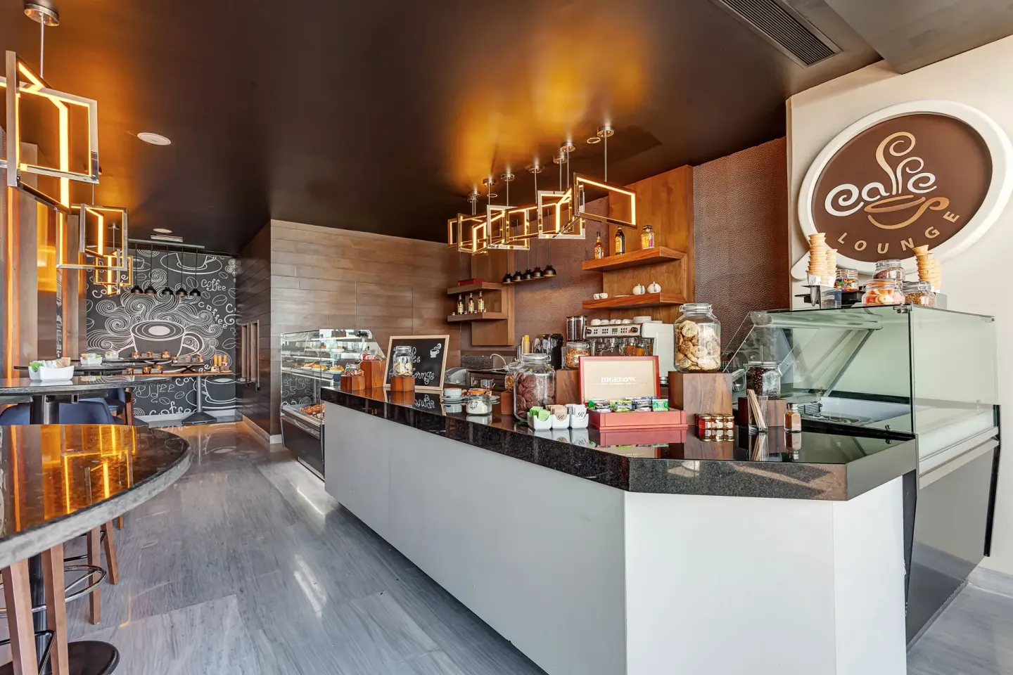 Cafe counter with pastry cases and coffee lounge sign at Royalton CHIC Cancun.