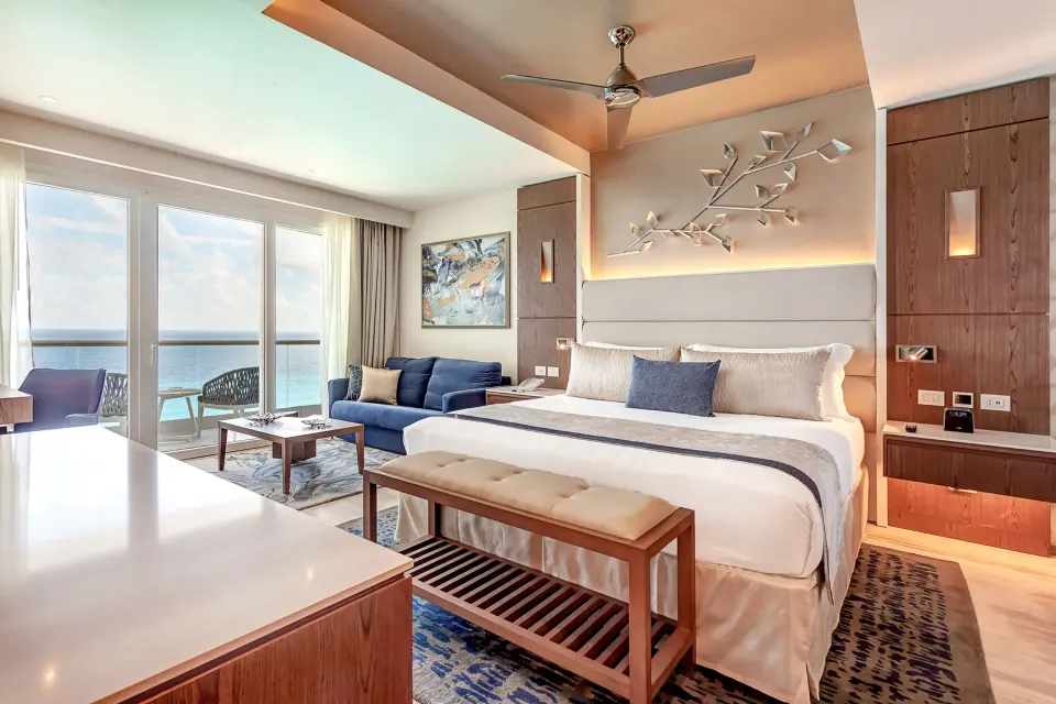 Luxury Junior Suite Ocean Front king bed, sofa, and bright ocean balcony at Royalton CHIC Cancun.