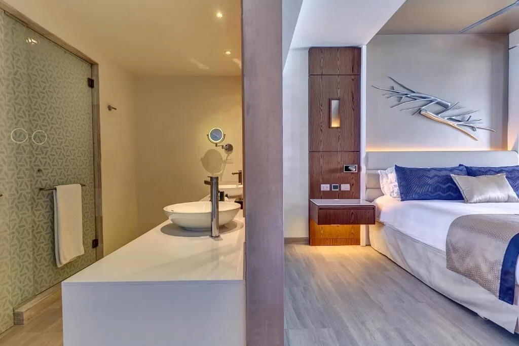 Luxury Junior Suite Sunset View at Royalton CHIC Cancun showing king bed and open vanity area.