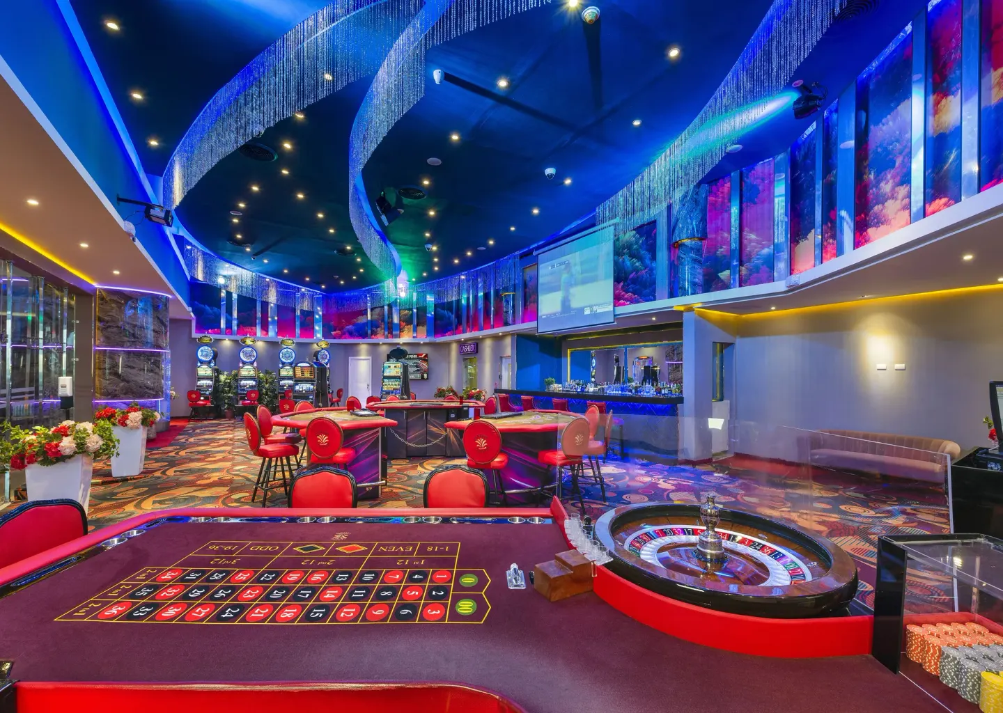 Casino floor at Royalton CHIC Punta Cana Resort & Casino with roulette, gaming tables, and blue lighting.