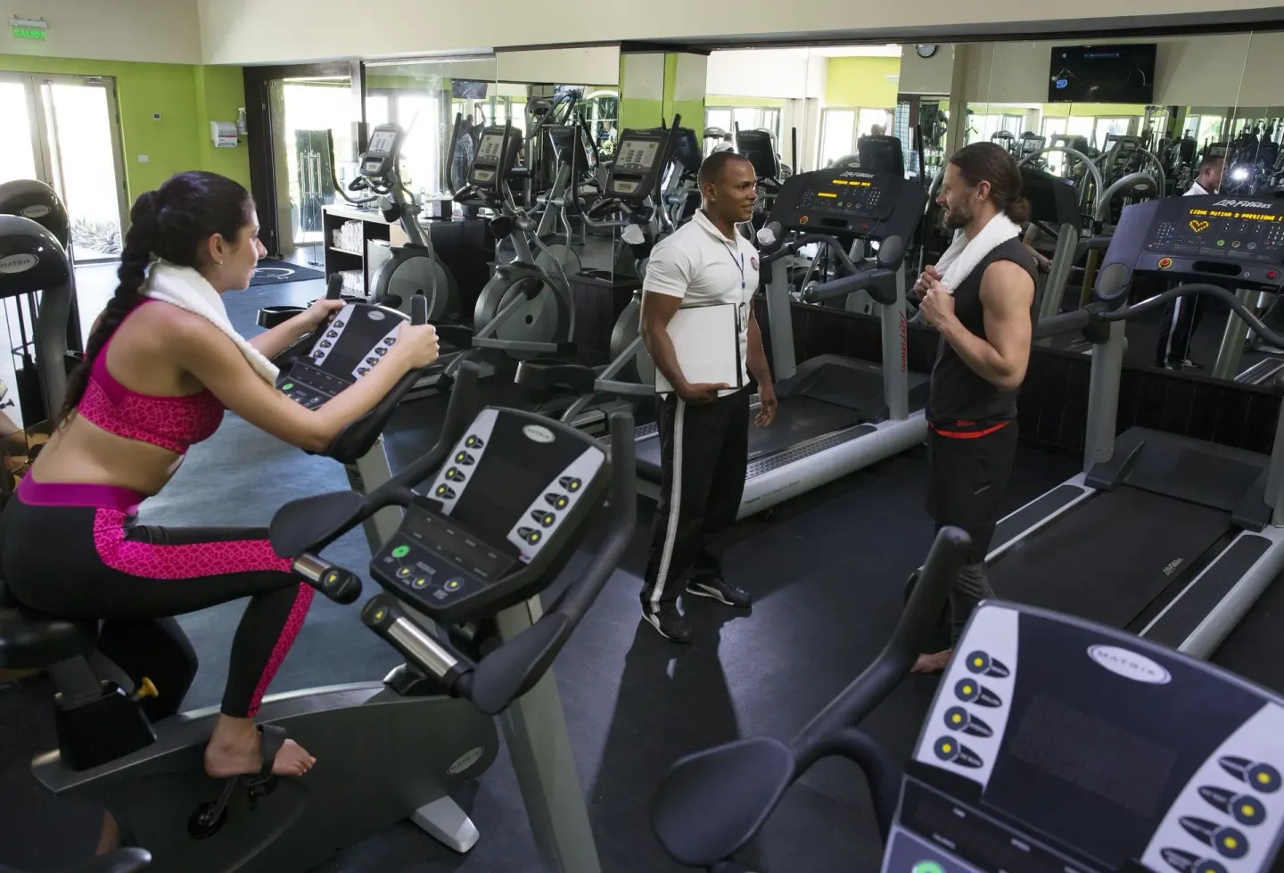 Guests and a trainer stand among cardio machines at Royalton CHIC Punta Cana Resort & Casino.