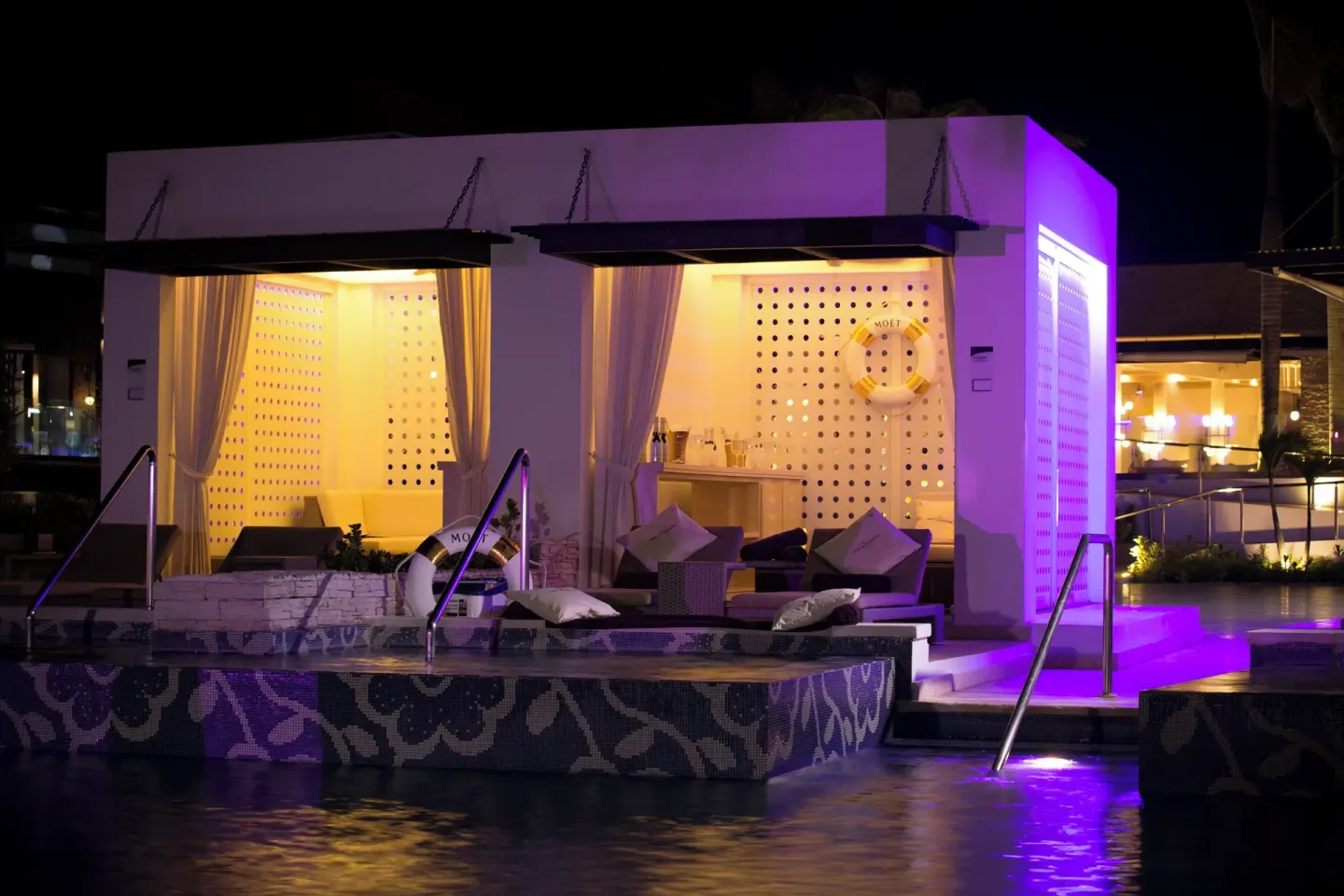 Private poolside cabanas illuminated at night at Royalton CHIC Punta Cana Resort & Casino.