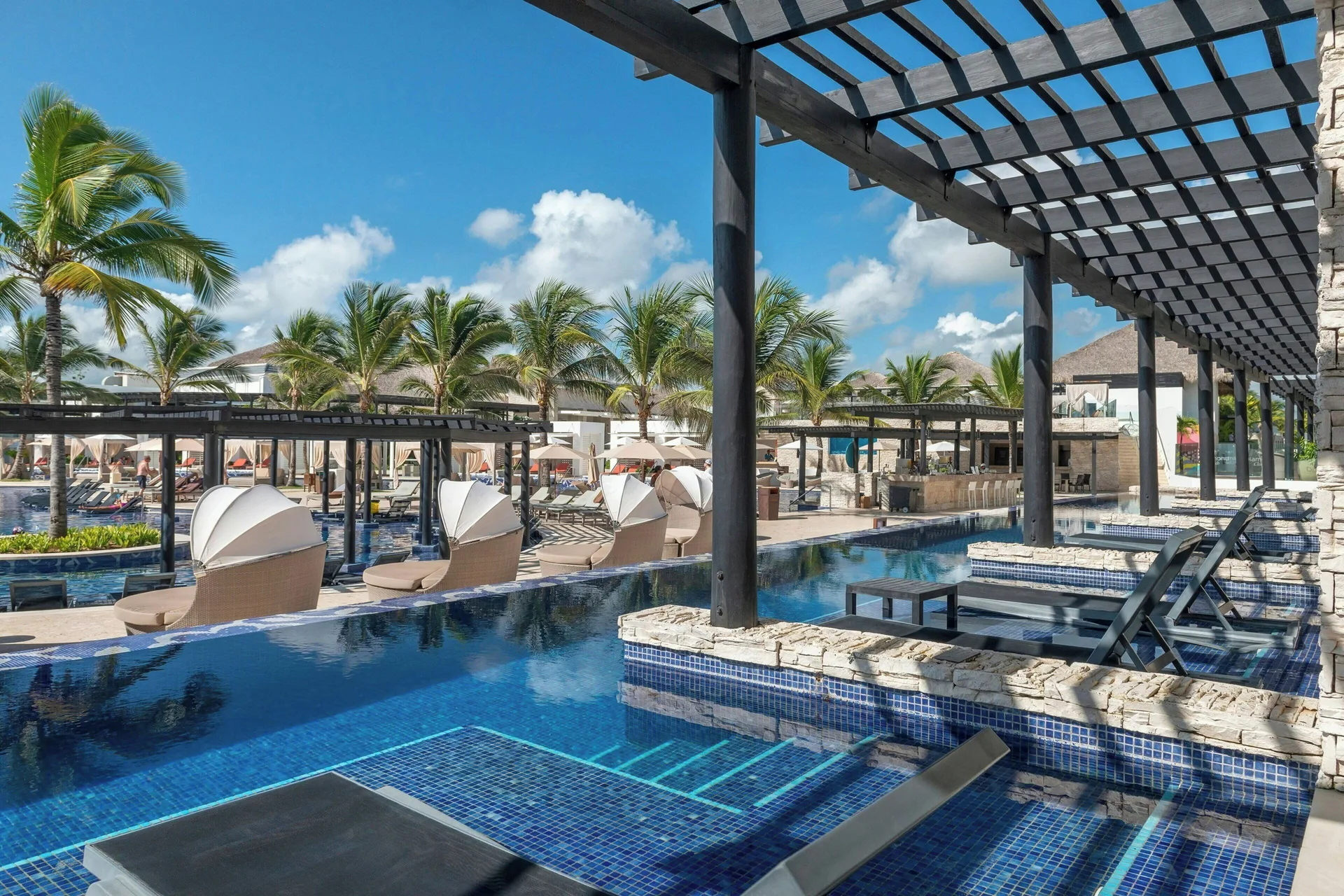 Pool loungers and cabanas under pergolas at Royalton CHIC Punta Cana Resort & Casino.