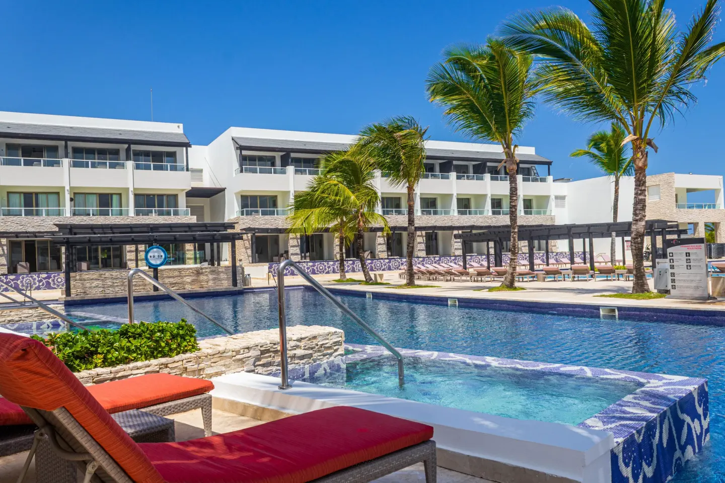 Pool terrace with palms and guest room buildings at Royalton CHIC Punta Cana Resort & Casino.