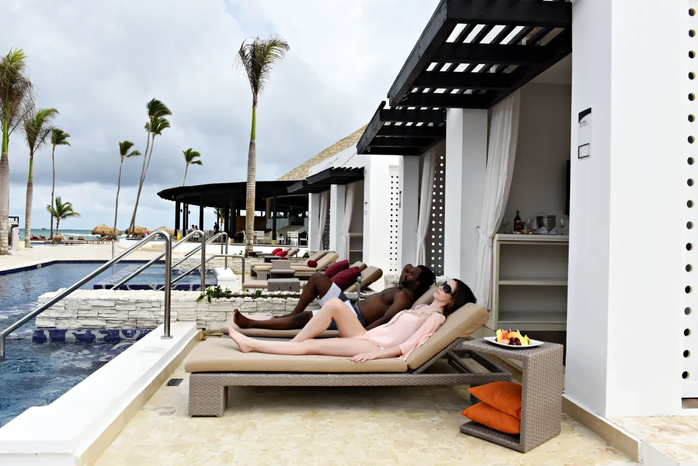 Guests reclining beside a pool cabana at Royalton CHIC Punta Cana Resort & Casino.