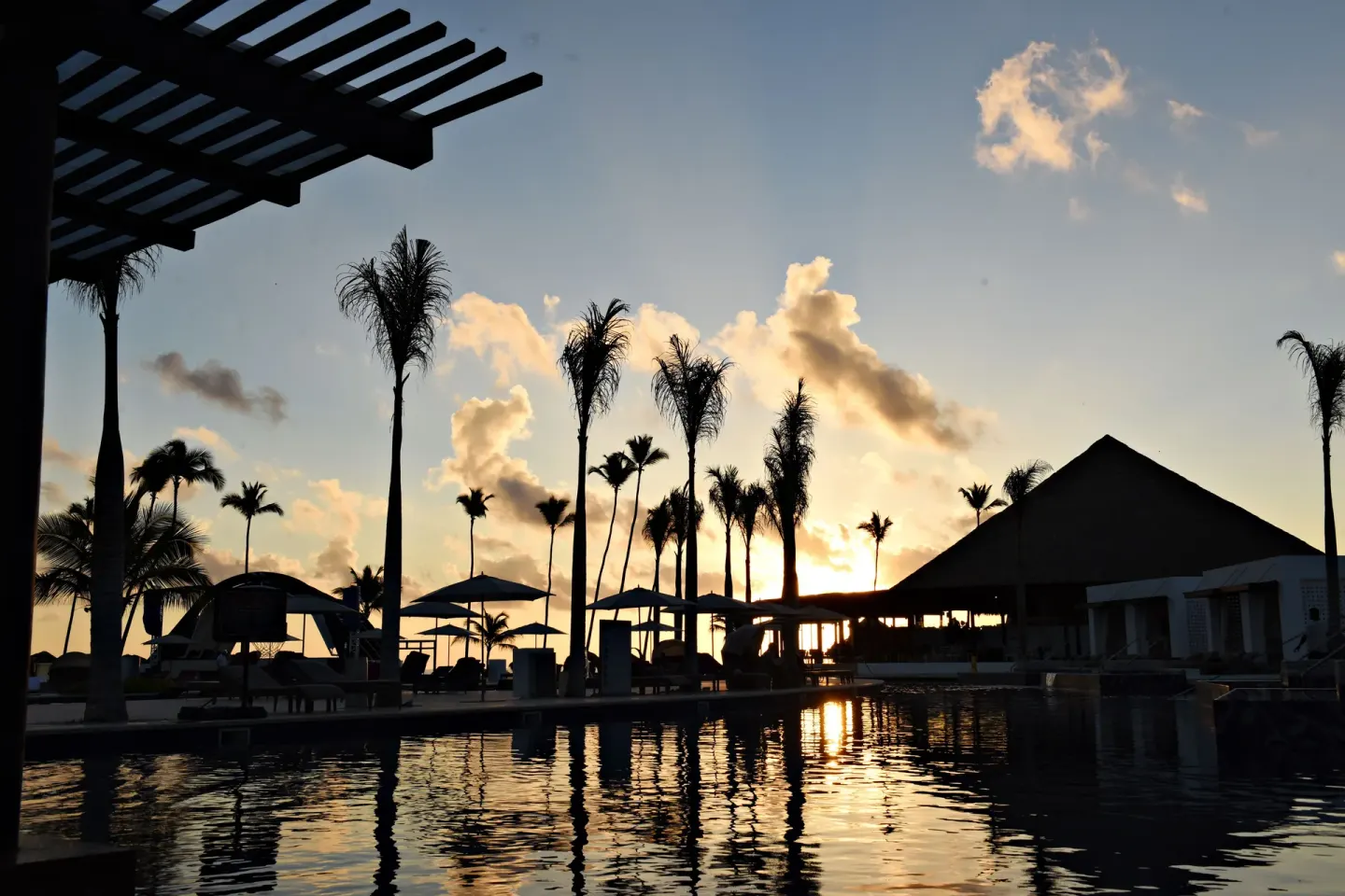 Sunset silhouettes palms and poolside cabanas at Royalton CHIC Punta Cana Resort & Casino.