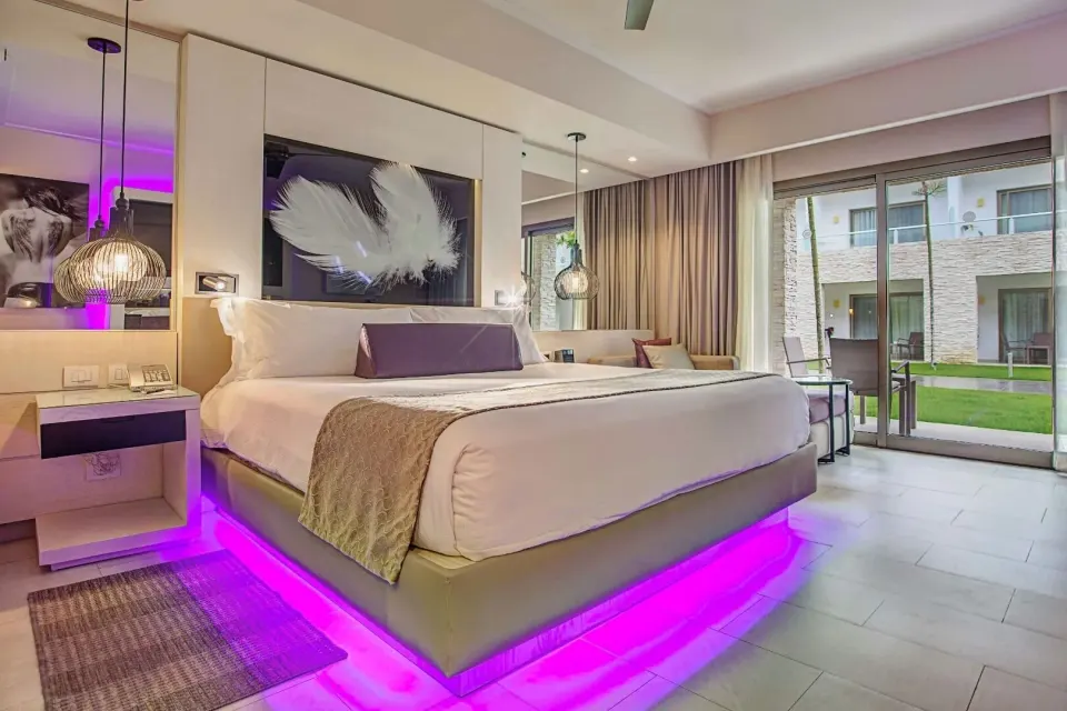 Luxury Room king bed beside sliding glass doors at Royalton CHIC Punta Cana Resort & Casino.