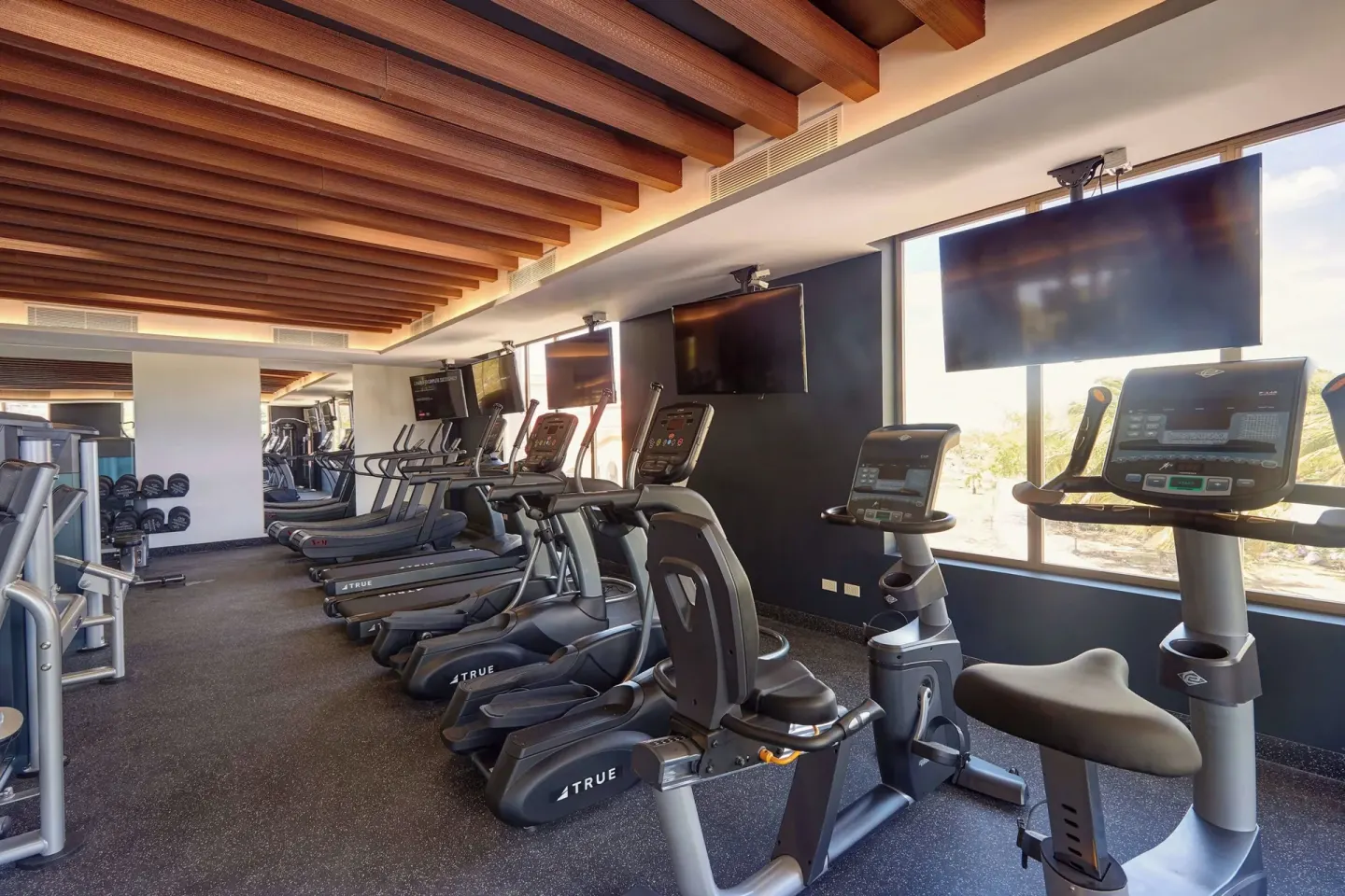 Treadmills, bikes, and wall-mounted screens in the fitness center at Royalton Grenada.