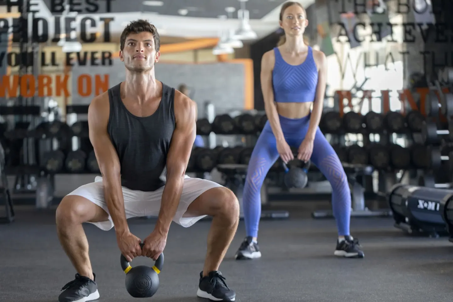 Two guests exercising with kettlebells in the fitness center at Royalton Grenada.