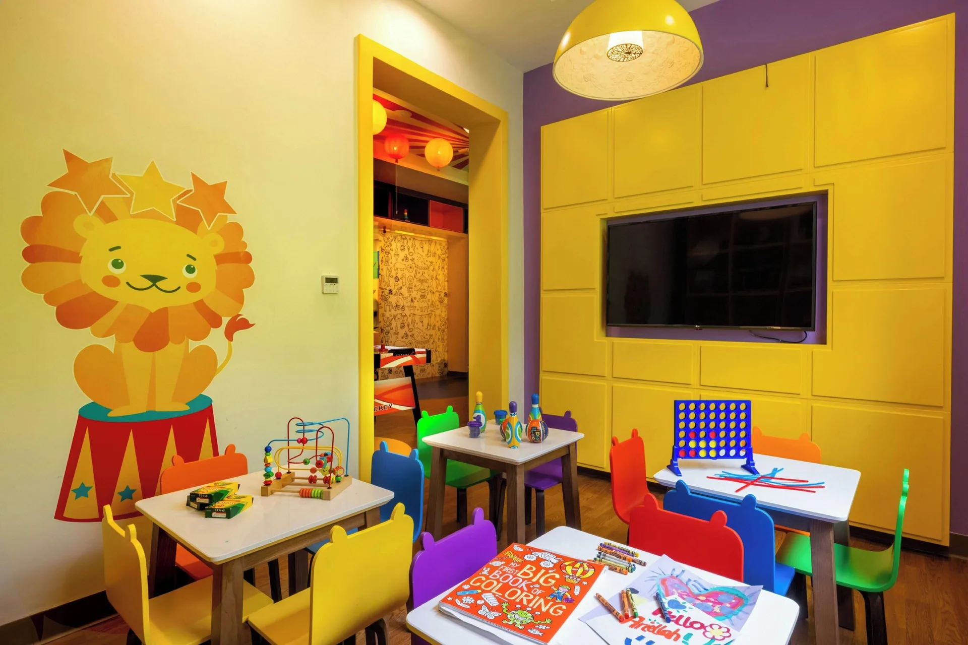 Kids activity room at Royalton Grenada with small tables, toys, games, and a lion mural.